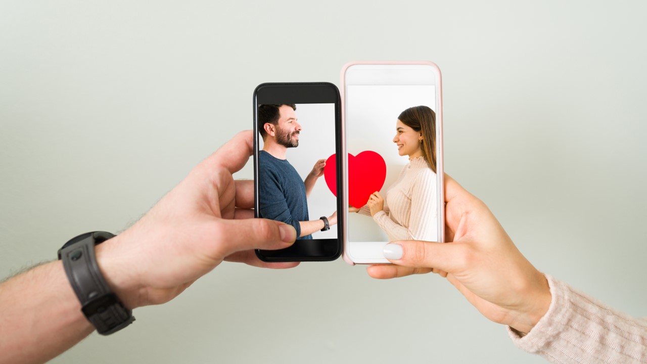 Mãos segurando celulares com imagem de homem e mulher na tela