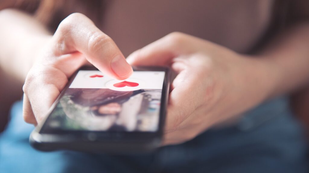 Pessoa tocando em tela do celular com coração e foto