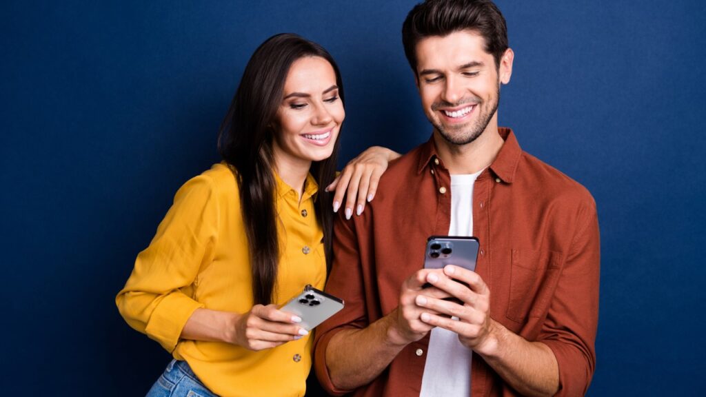 Casal sorrindo olhando celulares