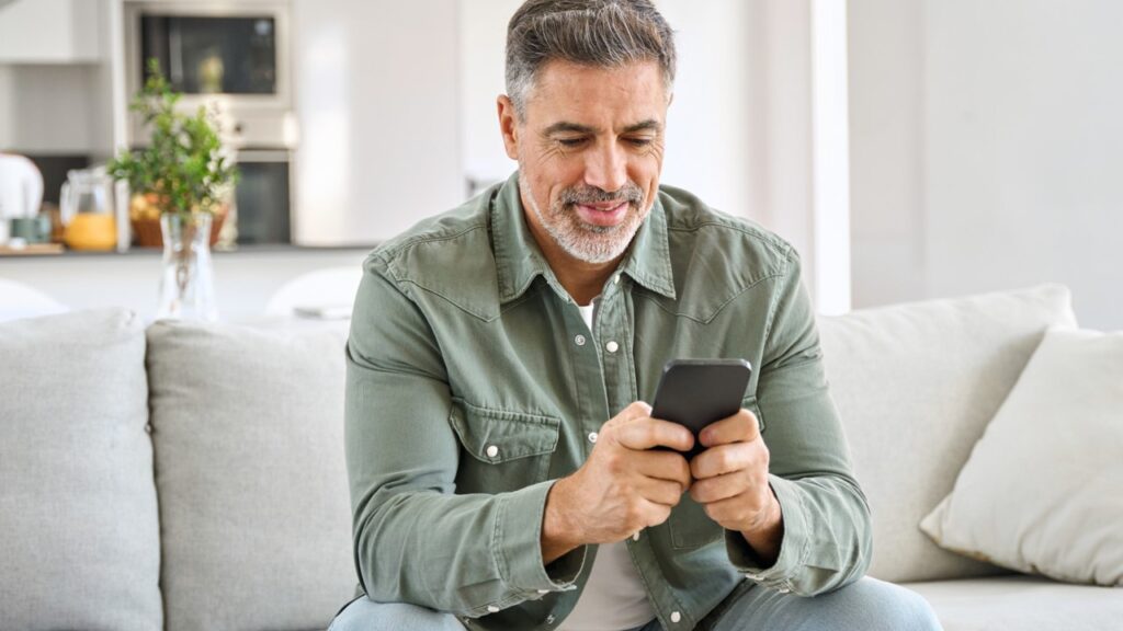 Homem mais velho sorrindo e olhando celular